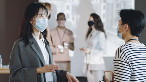 Asian-Women-in-Masks-Talking-on-Business-Event